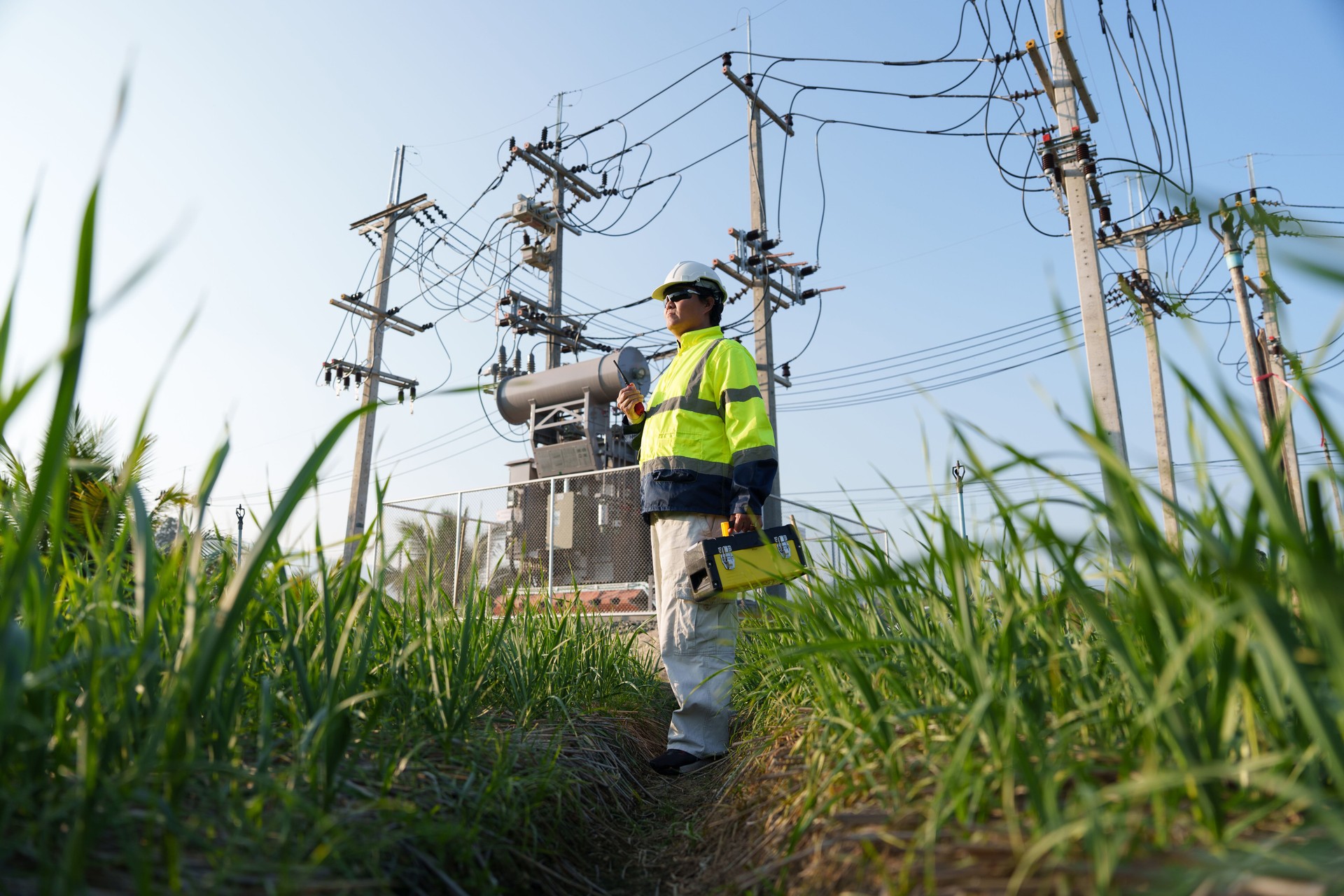 An expert engineer is inspecting a high-voltage transformer in a remote rural area.(Photo)